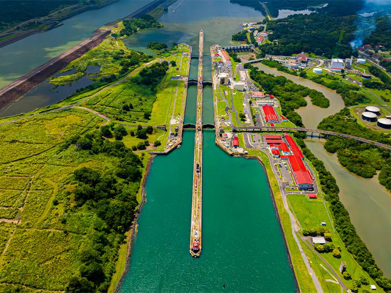 Imagen del Canal de Panamá con un barco en tránsito y paisajes verdes a su alrededor